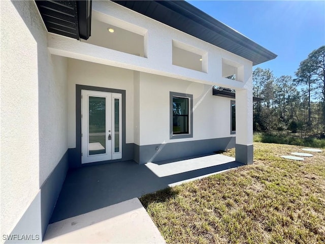 property entrance featuring french doors, a patio, and a yard