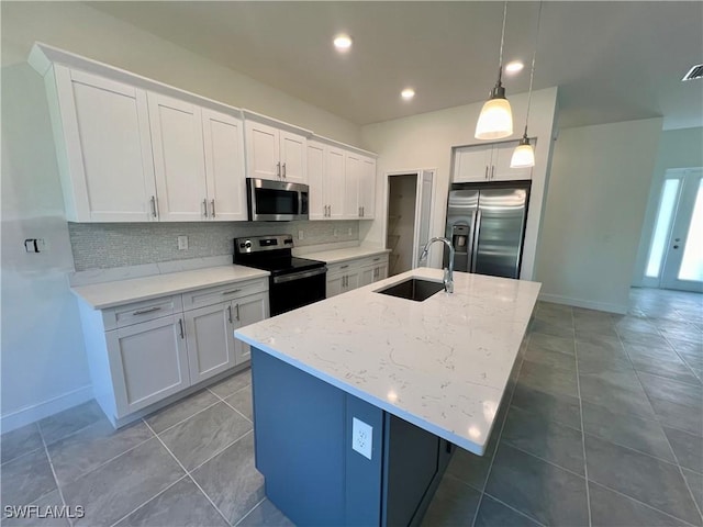 kitchen featuring stainless steel appliances, sink, white cabinetry, hanging light fixtures, and an island with sink