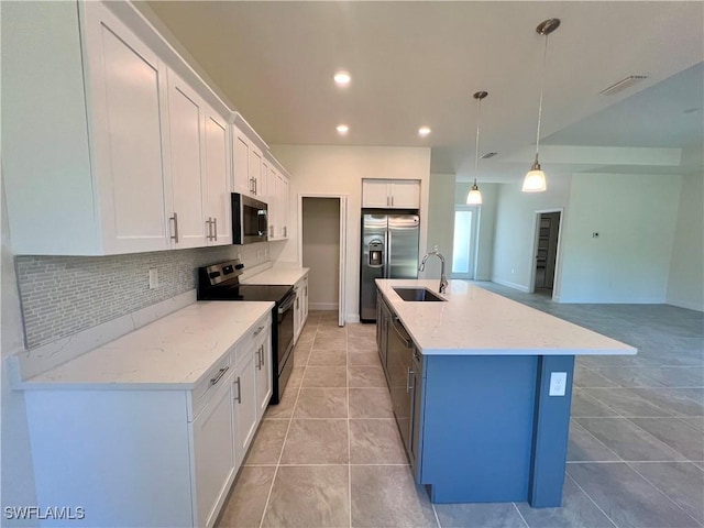 kitchen featuring white cabinets, hanging light fixtures, an island with sink, appliances with stainless steel finishes, and light stone counters