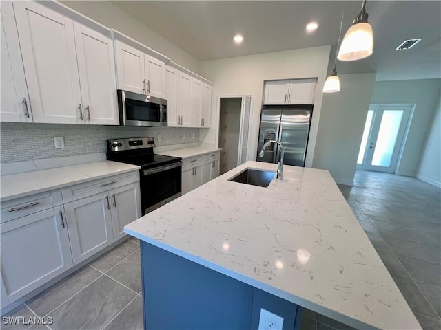 kitchen with white cabinetry, sink, hanging light fixtures, stainless steel appliances, and a kitchen island with sink