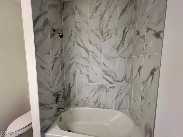 bathroom with tiled shower / bath combo and toilet