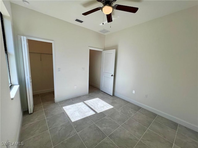 unfurnished bedroom featuring tile patterned floors, a spacious closet, a closet, and ceiling fan