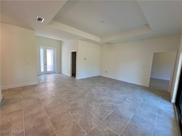 unfurnished room with a raised ceiling, french doors, and light tile patterned flooring