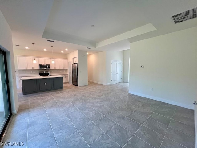 unfurnished living room with tile patterned floors and a tray ceiling