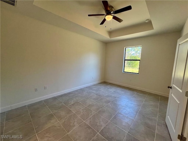 spare room with tile patterned flooring, a tray ceiling, and ceiling fan