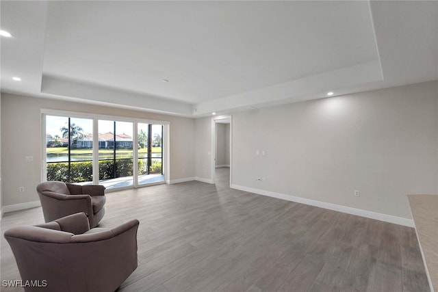 living room with light wood-type flooring and a tray ceiling