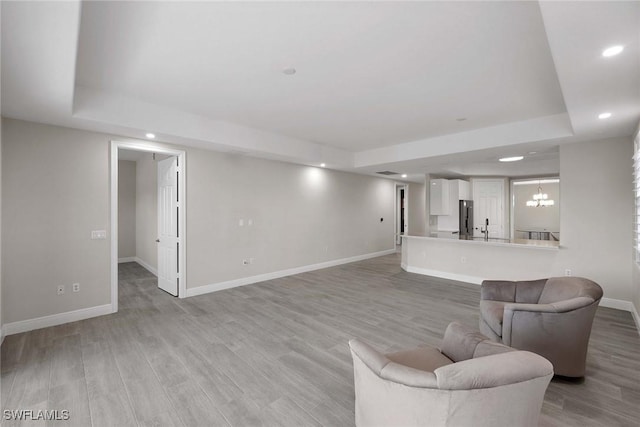 living room with light hardwood / wood-style floors and a tray ceiling