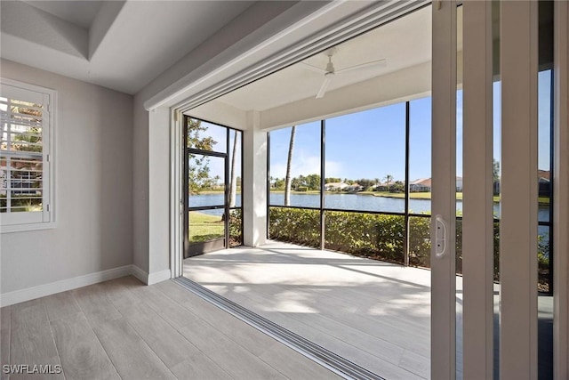 interior space with ceiling fan, light wood-type flooring, a water view, and a wealth of natural light