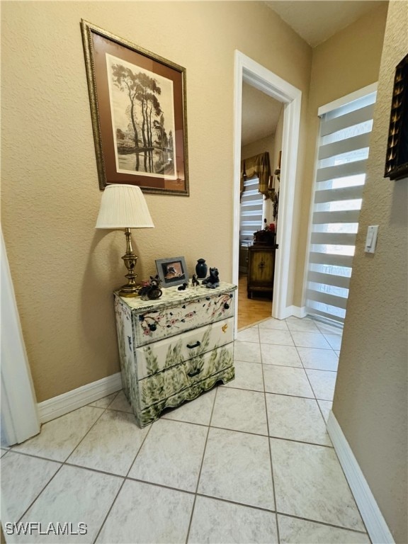 corridor with baseboards and light tile patterned floors