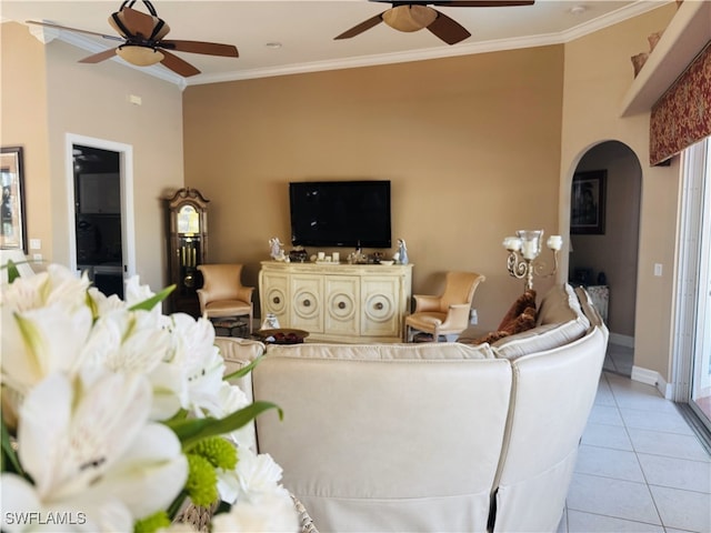 living room featuring ornamental molding, arched walkways, ceiling fan, and light tile patterned floors