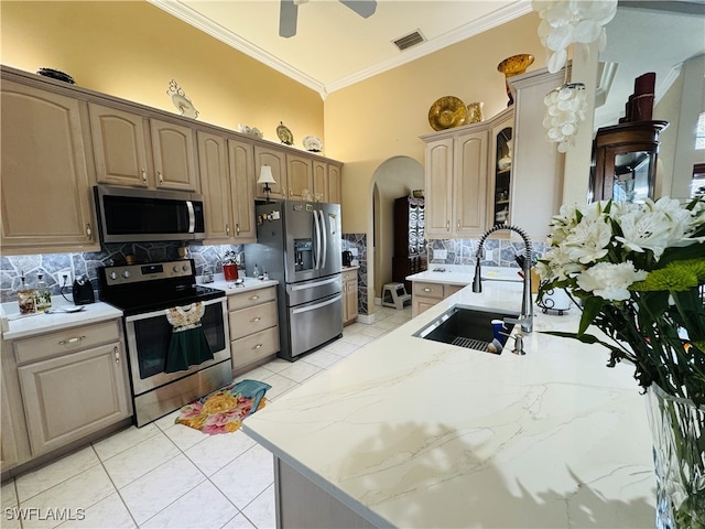 kitchen with tasteful backsplash, sink, crown molding, light tile patterned flooring, and appliances with stainless steel finishes