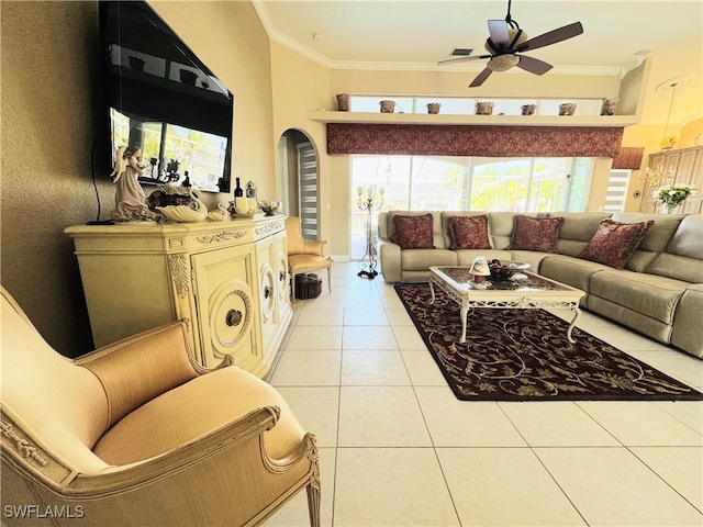 living room with light tile patterned floors, ceiling fan, arched walkways, and crown molding