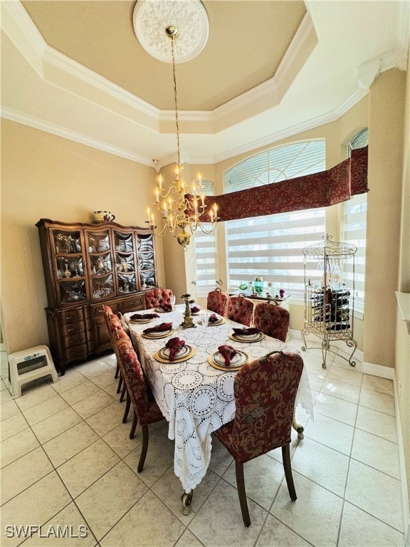 dining room featuring a notable chandelier, a raised ceiling, ornamental molding, light tile patterned flooring, and baseboards