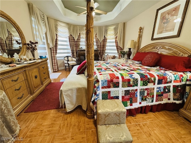 bedroom with ceiling fan, a tray ceiling, and crown molding