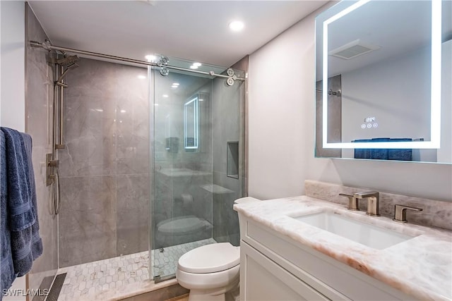 bathroom featuring a shower with door, vanity, and toilet