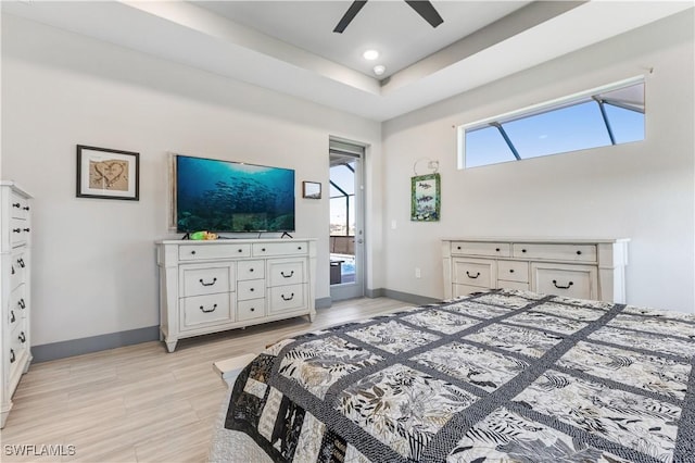 bedroom featuring connected bathroom, a tray ceiling, light hardwood / wood-style flooring, and ceiling fan