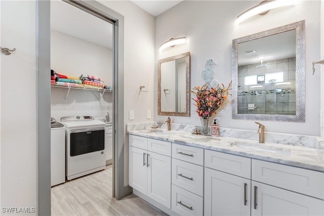 bathroom with hardwood / wood-style floors, vanity, washer and dryer, and a tile shower