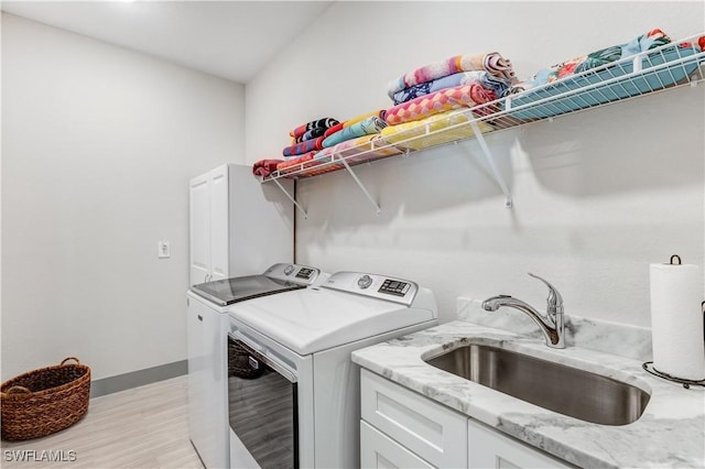 clothes washing area featuring sink, cabinets, and independent washer and dryer