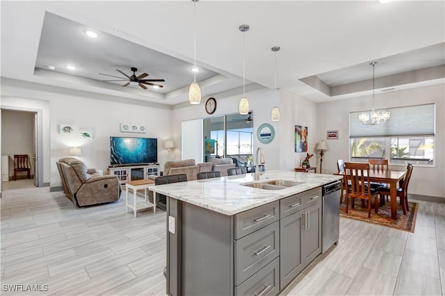 kitchen with pendant lighting, stainless steel dishwasher, sink, and a tray ceiling