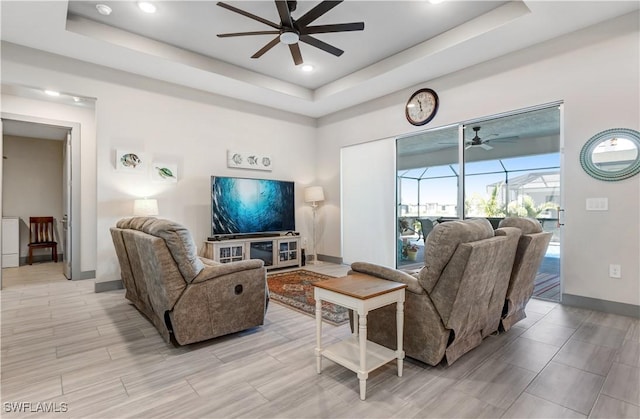 living room with a raised ceiling and ceiling fan