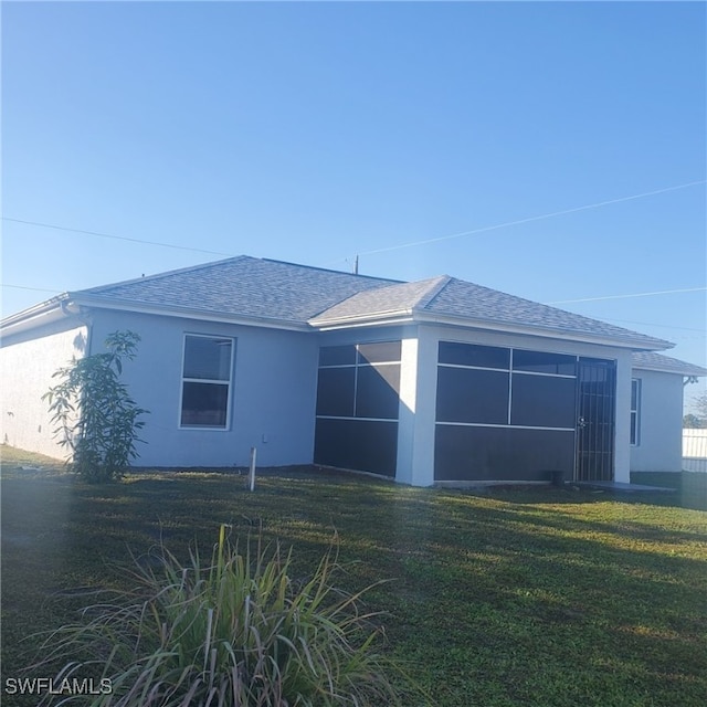 back of property featuring a lawn and a sunroom