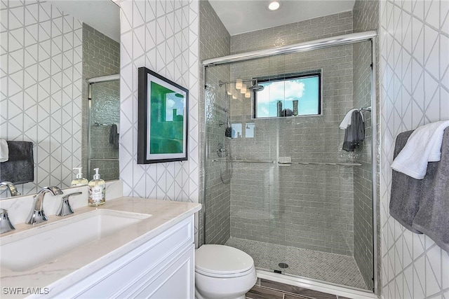 bathroom featuring an enclosed shower, vanity, toilet, and tile walls