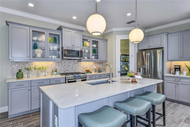 kitchen featuring hanging light fixtures, a kitchen island with sink, sink, and stainless steel appliances