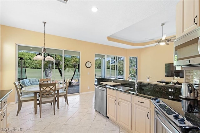 kitchen with a raised ceiling, sink, hanging light fixtures, dark stone countertops, and stainless steel appliances