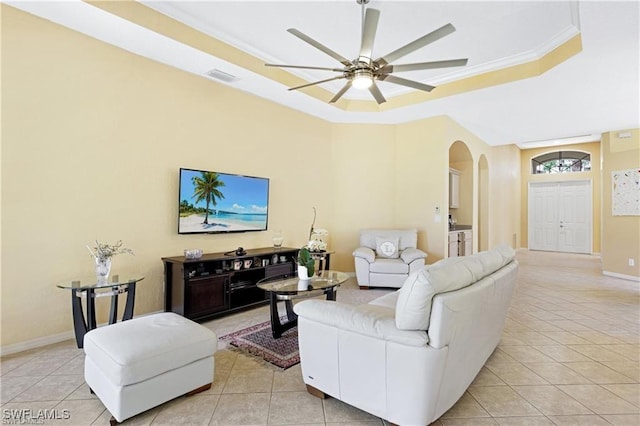 tiled living room with a tray ceiling, ceiling fan, and ornamental molding