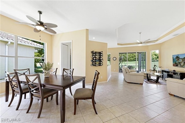 dining area with ceiling fan, a raised ceiling, light tile patterned floors, and crown molding