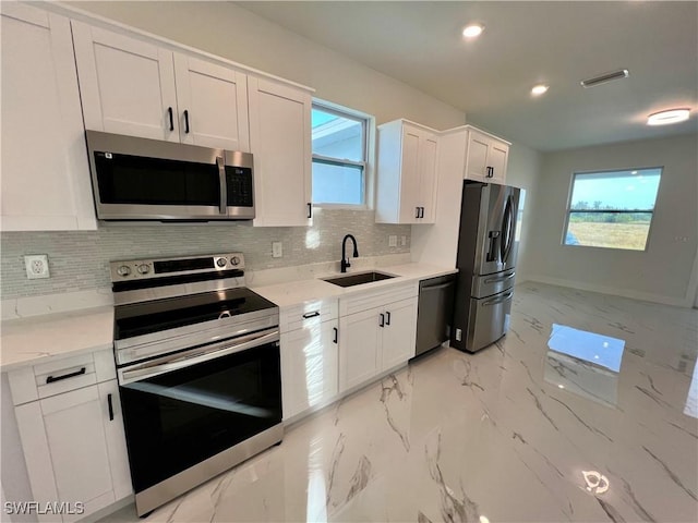 kitchen with backsplash, sink, light stone counters, white cabinetry, and stainless steel appliances