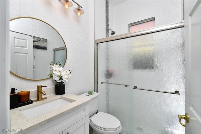 bathroom featuring vanity, toilet, and an enclosed shower