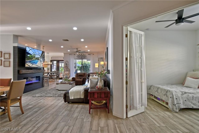 living room with crown molding, a fireplace, light hardwood / wood-style floors, and ceiling fan