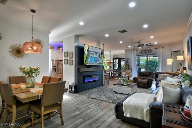 living room featuring ceiling fan, ornamental molding, a fireplace, and light hardwood / wood-style floors