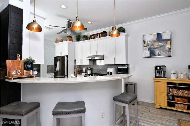 kitchen featuring white cabinetry, a breakfast bar area, stainless steel fridge, hanging light fixtures, and kitchen peninsula