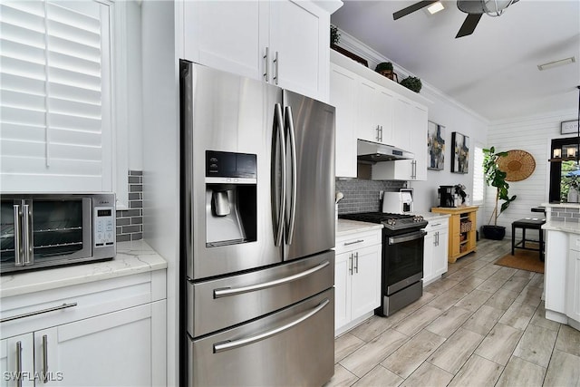 kitchen with white cabinetry, stainless steel appliances, light stone counters, and backsplash