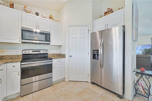 kitchen featuring white cabinets, dark stone counters, and stainless steel appliances