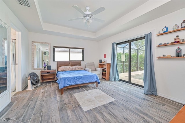 bedroom featuring access to outside, a raised ceiling, and ceiling fan