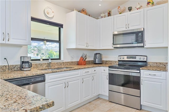 kitchen featuring light stone countertops, white cabinets, appliances with stainless steel finishes, and sink