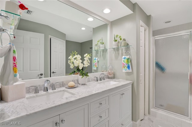 bathroom featuring a shower with door and vanity