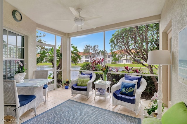 sunroom / solarium featuring ceiling fan, a wealth of natural light, and a water view