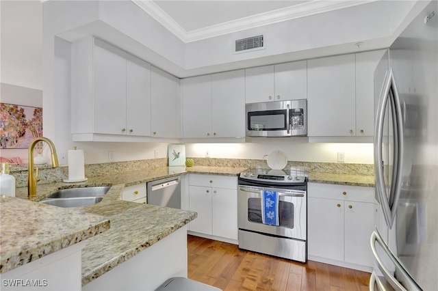 kitchen featuring stainless steel appliances, crown molding, light stone counters, white cabinets, and sink