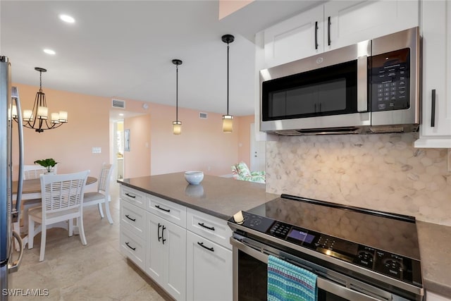 kitchen with appliances with stainless steel finishes, tasteful backsplash, a notable chandelier, white cabinets, and hanging light fixtures