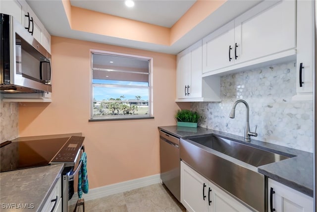 kitchen featuring a raised ceiling, white cabinetry, sink, and appliances with stainless steel finishes