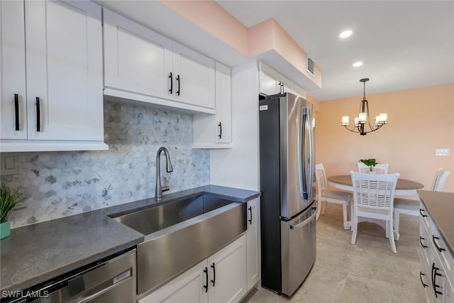 kitchen featuring sink, stainless steel appliances, a notable chandelier, backsplash, and white cabinets