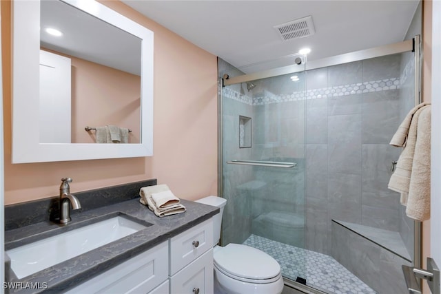 bathroom with walk in shower, vanity, and toilet