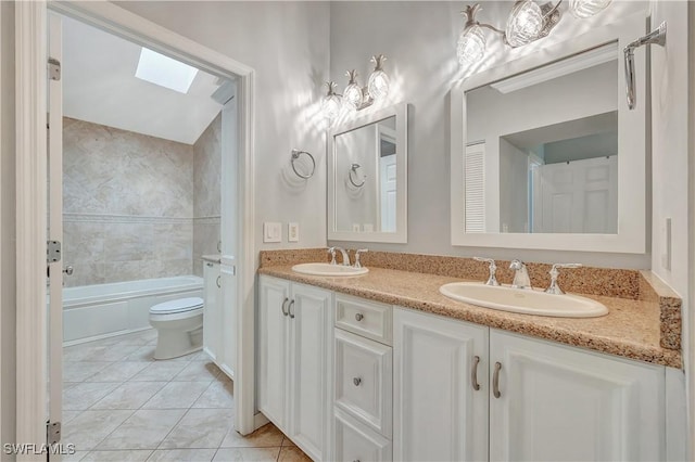 full bathroom with a skylight, tile patterned floors, toilet, vanity, and tiled shower / bath