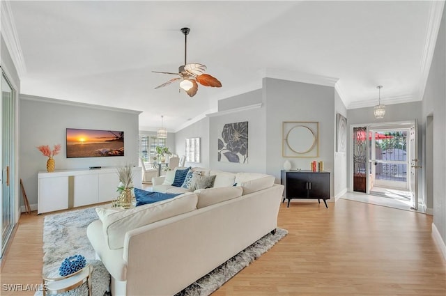 living room with ceiling fan with notable chandelier, light hardwood / wood-style floors, and ornamental molding