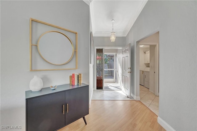 foyer with washer and dryer, ornamental molding, and light hardwood / wood-style flooring