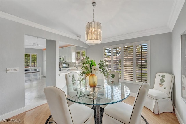 dining room with crown molding, a healthy amount of sunlight, ceiling fan with notable chandelier, and light hardwood / wood-style floors